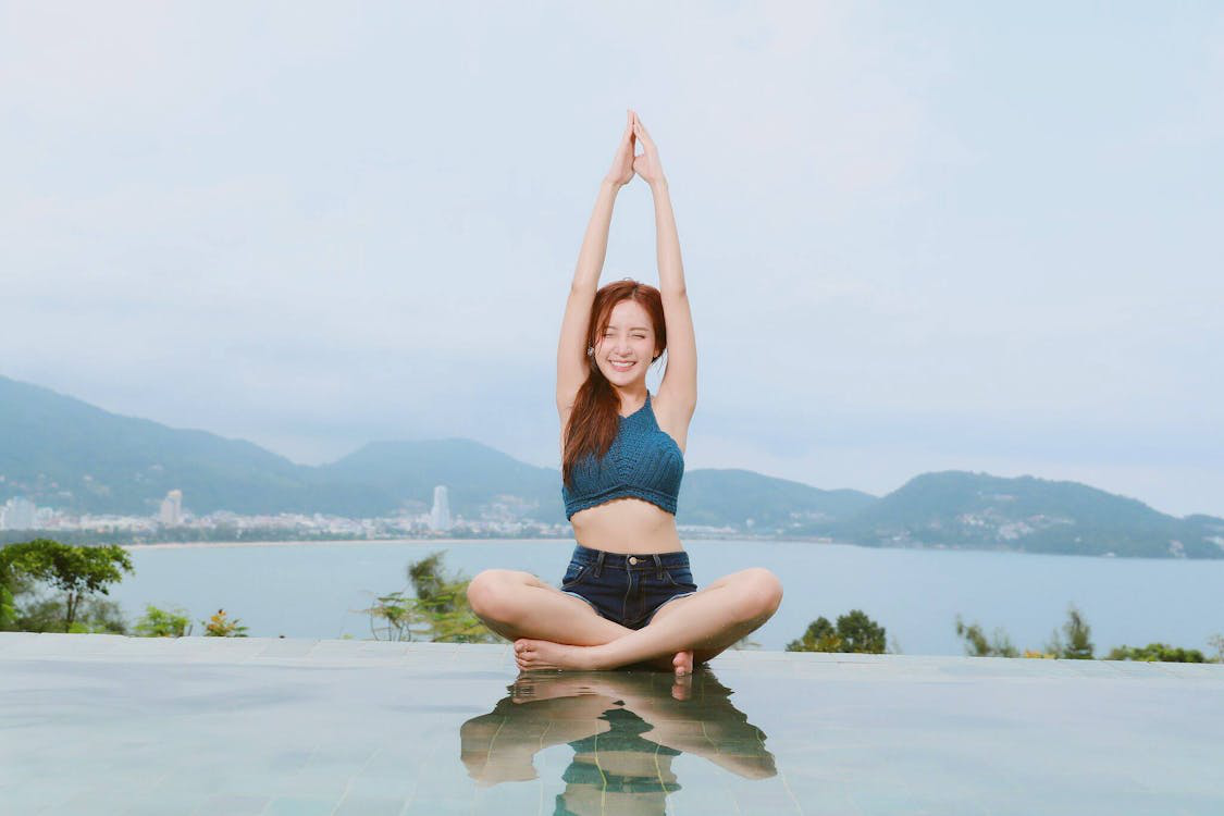 A smiling person doing yoga near a waterbody